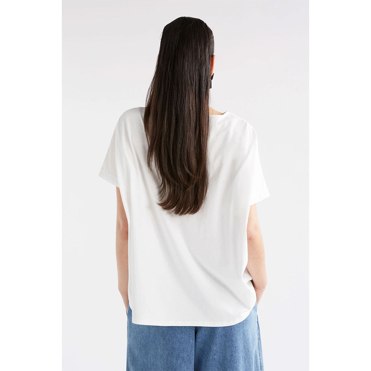 Back view of a model wearing a white tshirt with jeans.