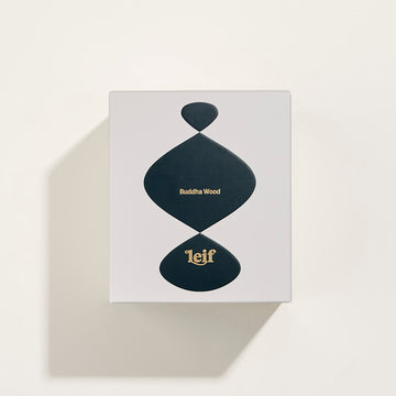 Front view of a brown glass candle with the text 'Buddha Wood Bougie Parfumee 208g' and the Leif logo.