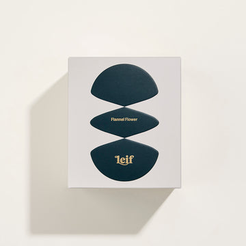 Front view of a white glass candle with the text 'Flannel Flower Bougie parfumee 280g' and the Leif logo.