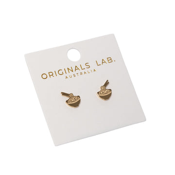 Pair of gold earrings shaped like a noodle bowl on a 'Originals Lab.' branded card against a white background.