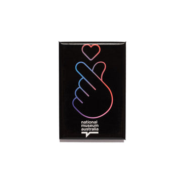A black rectangle magnet with a coloured outline of a hand making a heart gesture.