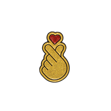 A metal magnet shaped like a hand making a heart symbol.