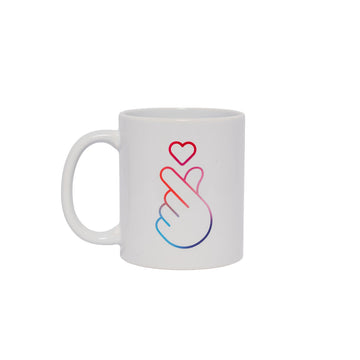 A white ceramic mug with a line drawing of a hand making a heart symbol.