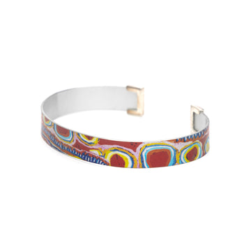 A bangle standing up and printed with artwork by Murdie Morris.