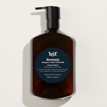 A clear pump bottle with a black lid. The brown hand wash can be seen inside with a dark blue circle sticker in the middle of the bottle with product information.