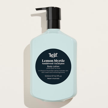 A pale blue bottle with a black pump lid and a dark blue circle in the middle. The text 'Leif Lemon Myrtle Sandalwood Eucalyptus Body Lotion' is written in white in the circle along with further product information.