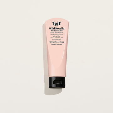 A small pink tube of body lotion with a black lid and product information written in black on the front.