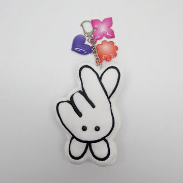 Keychain with cartoon hand sign and colorful charms on a light gray background