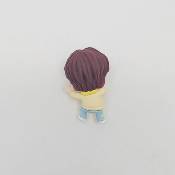 Small figurine of a cartoon character with brown hair on a light gray background.
