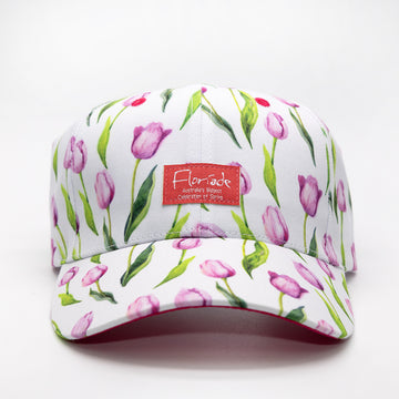 A white cap printed with purple tulips and a red tag on the front with the text 'Floriade Australia's Biggest Celebration of Spring'.