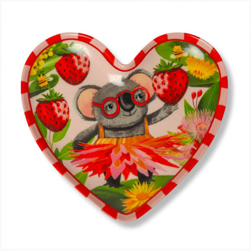 A heart shaped trinket tray illustrated with a koala wearing a dress and holding a strawberry.