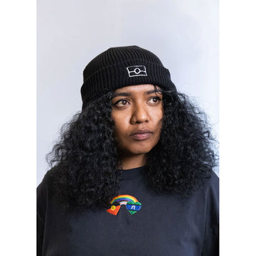 Front view of a model wearing a black beanie with a black jumper.
