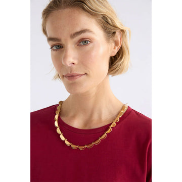 Gold necklace with scalloped design on a white background.