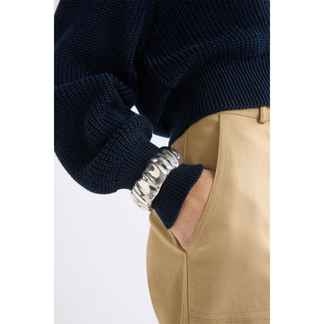 Gold bangle with a textured design on a light gray background.