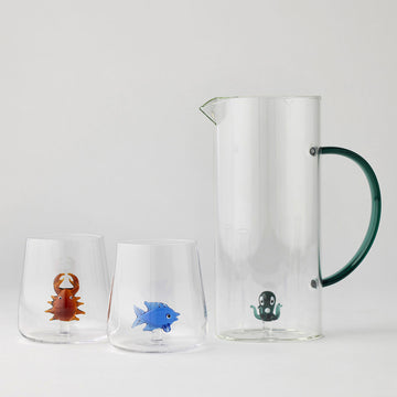 Clear glass pitcher and two tumblers with colourful glass sea animals inside the jug and glasses.