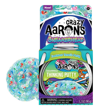 An open card packet titled 'Crazy Aarons Sneakerhead Footwear Fanatic Putty' with a round container inside. There is some light blue putty next to the box filled with sneaker shaped pieces.