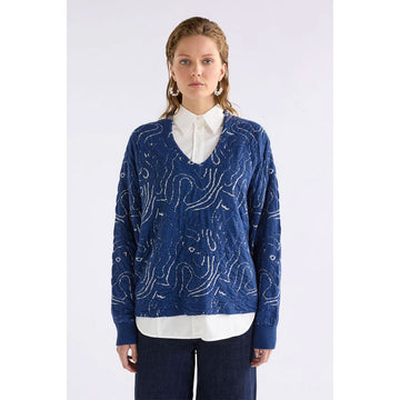 Blue sweater with white abstract patterns on a white background.