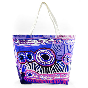 A large tote bag printed with artwork by Murdie Nampijinpa Morris in purple.
