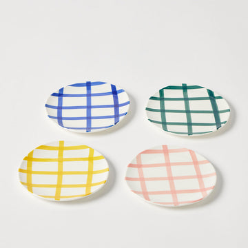 Four round ceramic plates with plaid patterns in blue, green, yellow, and pink on a white background.