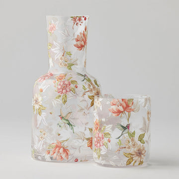 Floral-patterned glass carafe and glass on a light gray background.