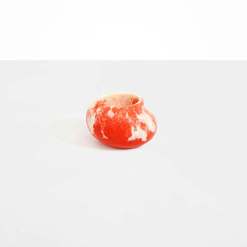 A small irregular shaped round vase in orange pink resin.