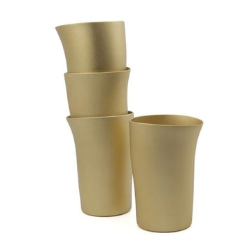 Set of four gold-colored tumblers on a white background.