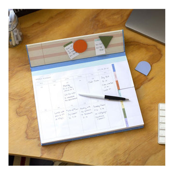 Weekly desk planner with blue grid design and brown sleeve on a white background
