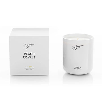 A white candle next to a matching white box with the text 'Sohum Peach Royale' written on both items.