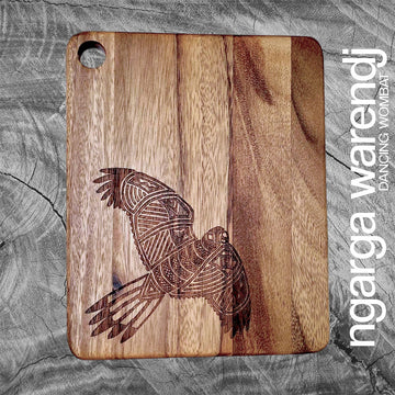 Wooden cutting board with a bird design on a gray background, featuring the brand 'ngarga warendj'.