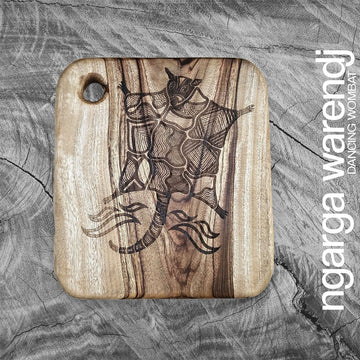 Wooden cutting board with a engraved design of a possum on a textured gray background, featuring the brand 'ngarga wardendj'.