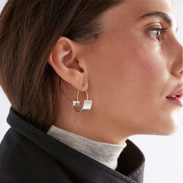 A small hoop earring with a round flat bottom in a Gold finish.