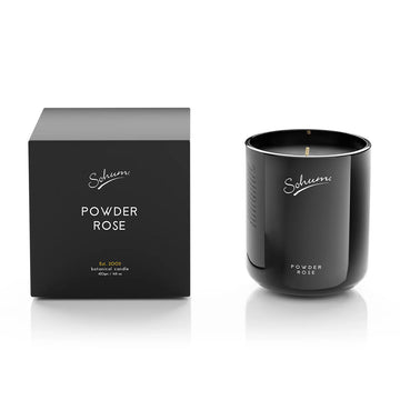 A black candle next to a matching black box with the text 'Sohum Powder Rose' written on both items.