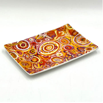 A ceramic rectangle tray printed with artwork by Cedric Varcoe in shades of red and yellow.