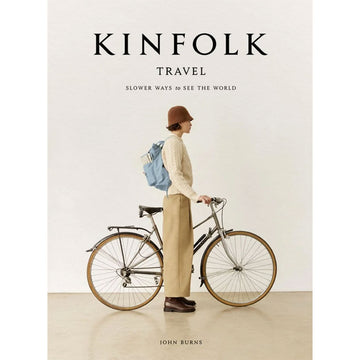 'Kinfolk Travel' book cover featuring a photo of side view of a woman standing next to a bicycle.