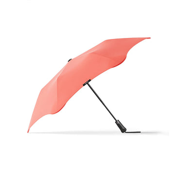 An open umbrella in a coral pink colour with a black handle.