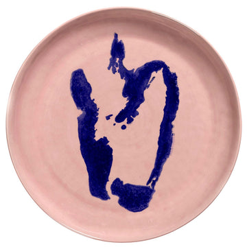 Top down view of a pink plate with blue abstract design on a white background.