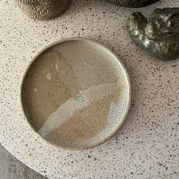 Ceramic plate with textured surface on a speckled countertop.