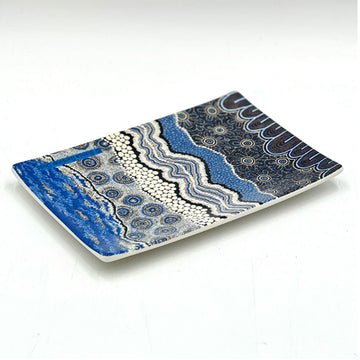 A ceramic rectangle tray printed with artwork by Bianca Gardiner Dodd in blue, white and grey.