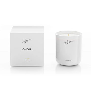 A white candle next to a matching white box with the text 'Sohum Jonquil' written on both items.