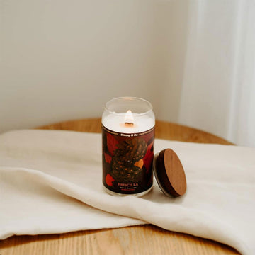 A candle in a can shaped container illustrated with a black cockatoo on the front.