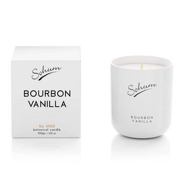 A white candle next to a matching white box with the text 'Sohum Bourban Vanilla' written on both items.
