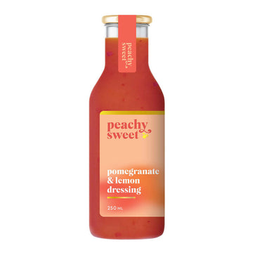 A bottle filled with orange coloured dressing with a label and the heading 'Peachy Sweet Pomegranate & Lemon Dressing'.
