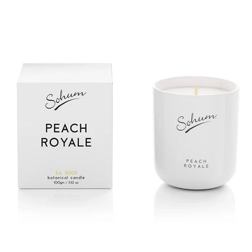 A white candle next to a matching white box with the text 'Sohum Peach Royale' written on both items.