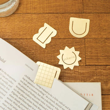 A set of metal paperclips with geometric designs on a striped background