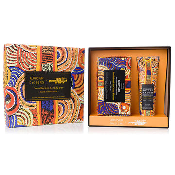 A boxed set with a body bar and tube of hand cream inside. All items are printed with artwork by Nora Nyutjangka in orange and blue.