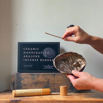 Ceramic handcrafted abalone incense burner with packaging on a wooden surface.