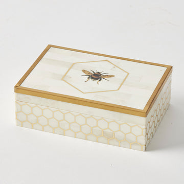A wooden rectangle box with an image of a bee on the top and a gold hexagon pattern around the box.