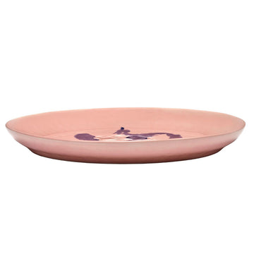Top down view of a pink plate with blue abstract design on a white background.