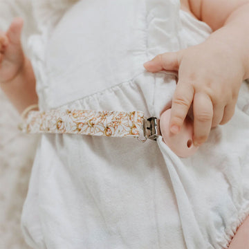 A dummy clip attached to a strap illustrated with gumnut babies by May Gibbs.