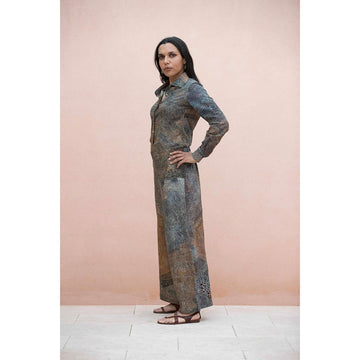 Woman wearing a First Nations artwork printed shirt and pants against a pink background.